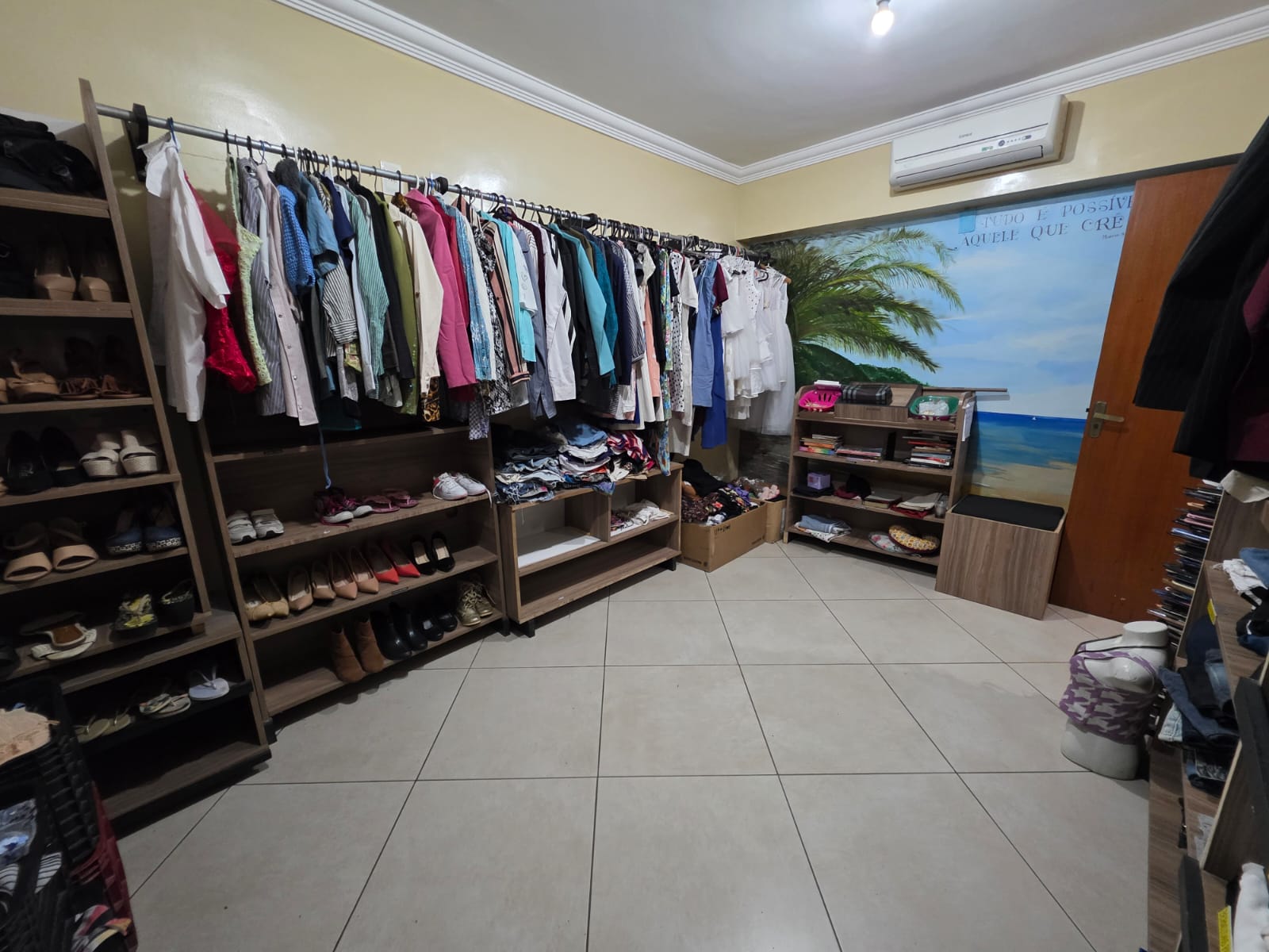 Interior do Bazar Solidário da CAPEC com araras de roupas organizadas