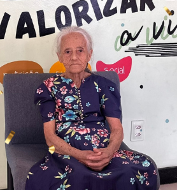 Dona Ilza, assistida pela CAPEC, posando para foto no painel da casa